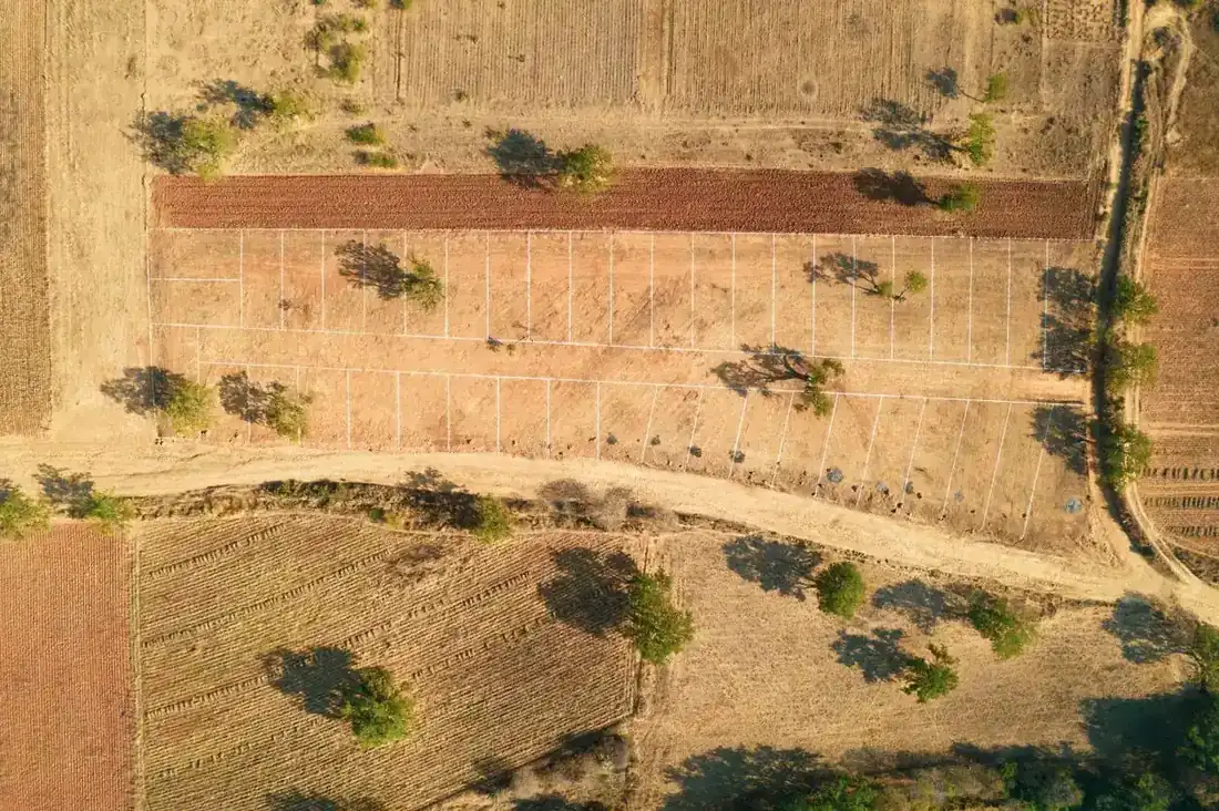 Aerial view of empty land divided into marked residential plots among fields