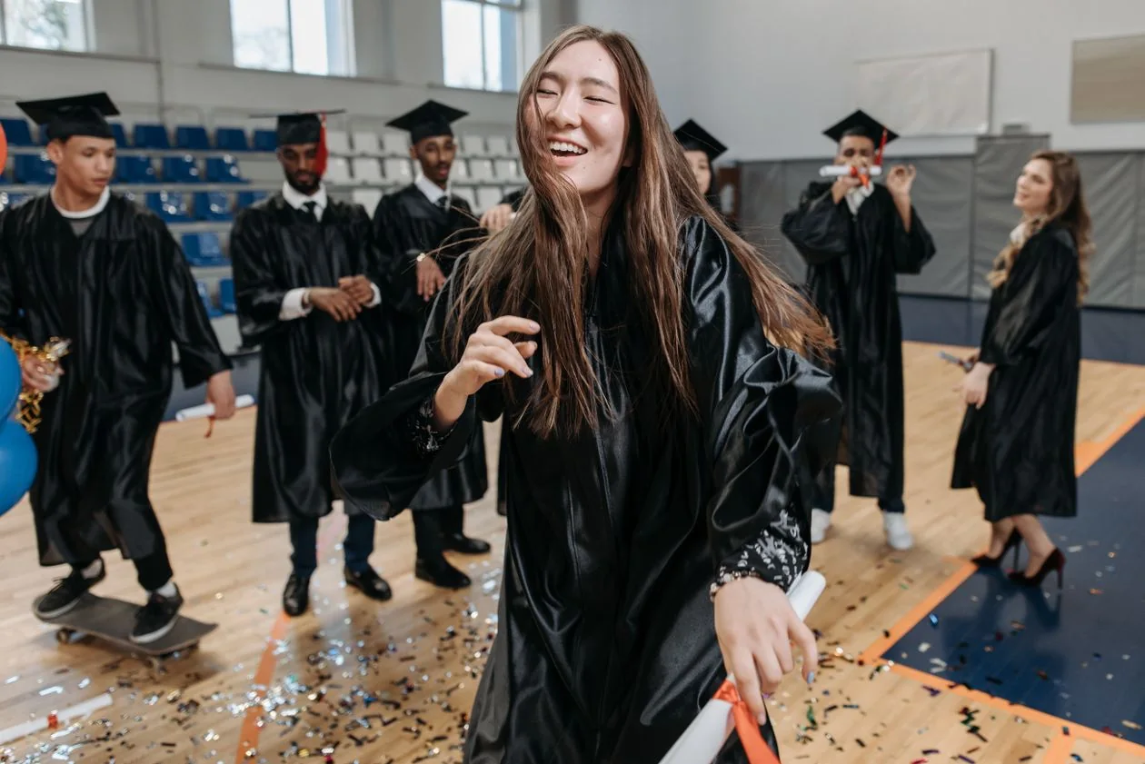 Happy graduates in black gowns celebrating with their diplomas at a convocation