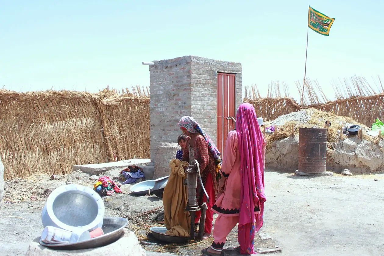 Women drawing water from a hand pump outside their homes in a rural village in Shikarpur, Pakistan.