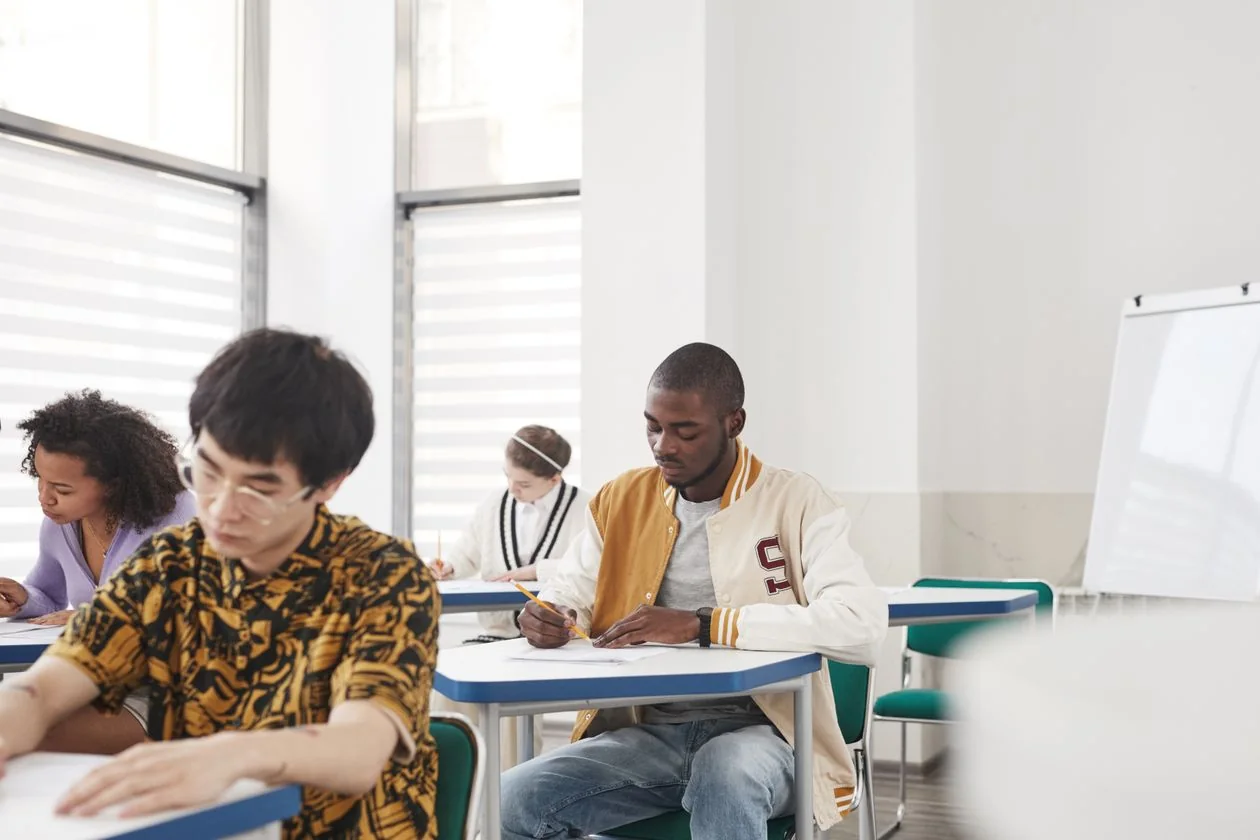 Candidates writing a recruitment test at desks in a bright examination classroom